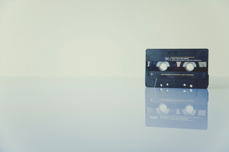 A black cassette tape on a white reflective surface